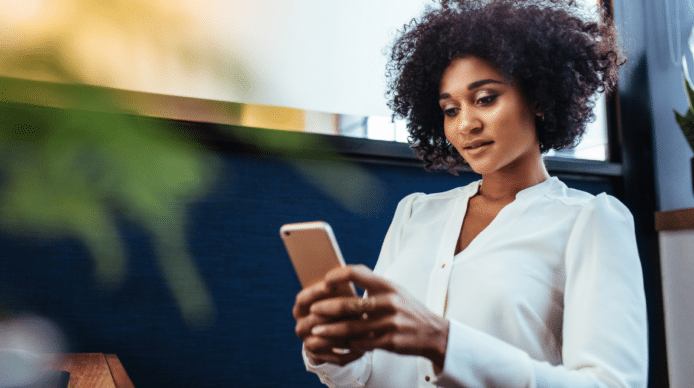 Woman outdoors in business casual blouse looking at an iPhone